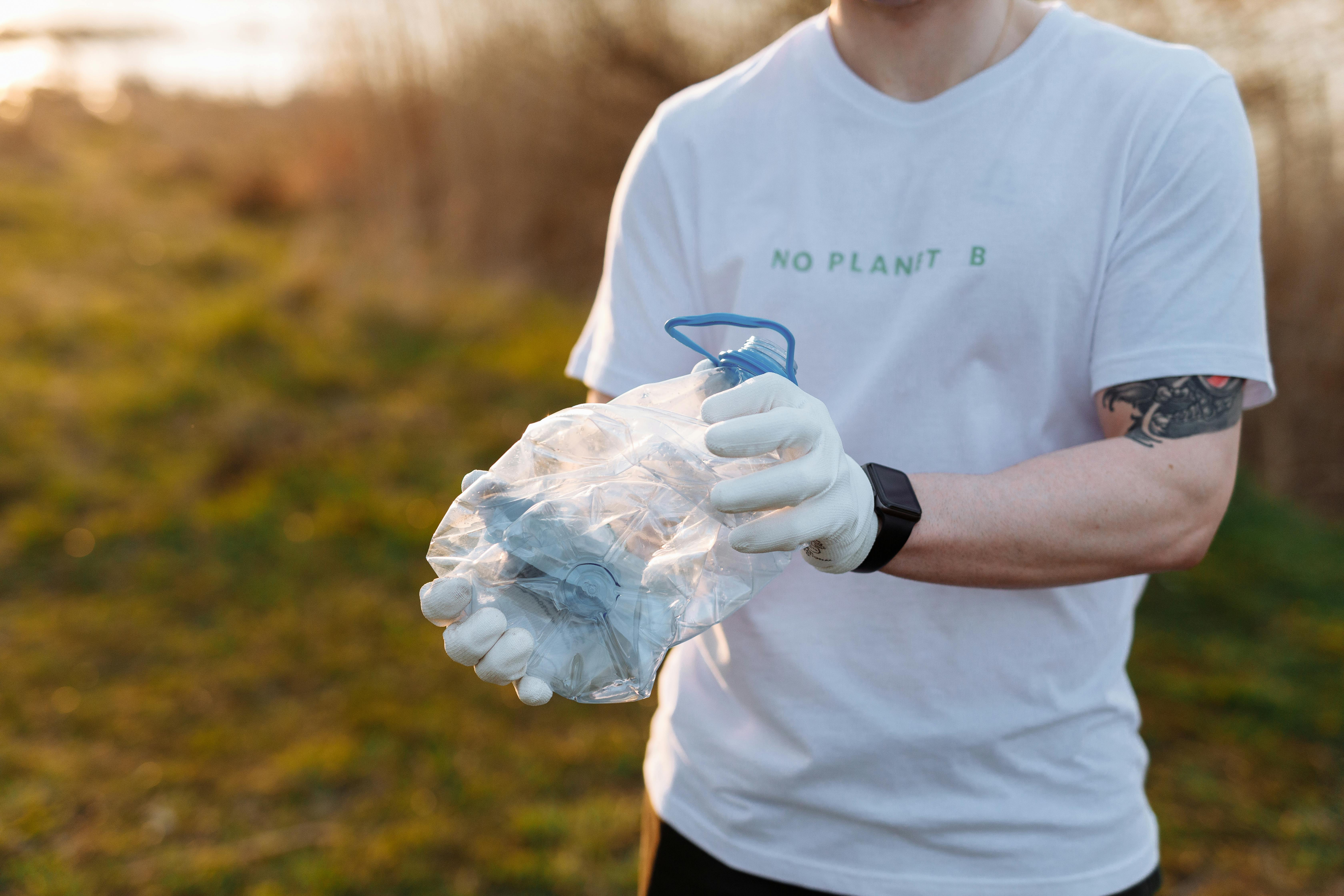 A person with gloves holding a crashed plastic bottle as part of recycling tutorials for lead magnets